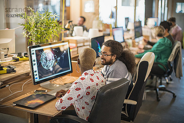 Designers meeting  working at computer in open plan office