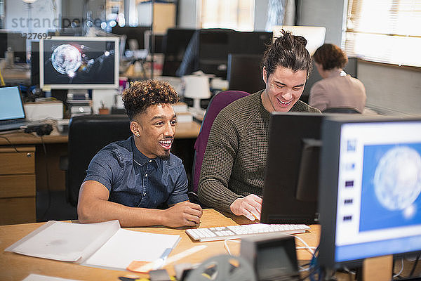 Creative businessmen working at computer in open plan office