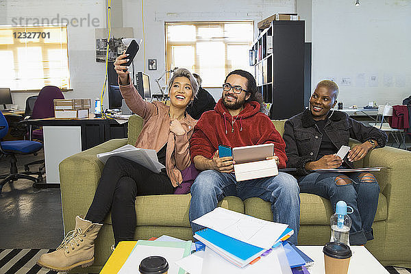 Happy creative business people taking selfie in casual open plan office