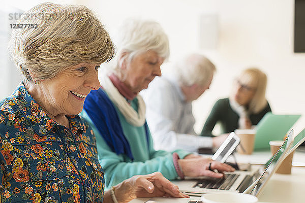 Senior women using laptops in conference room meeting