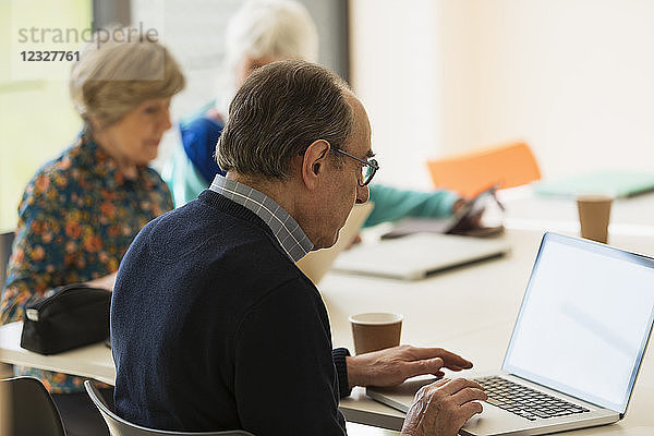 Senior businessman using laptop in meeting