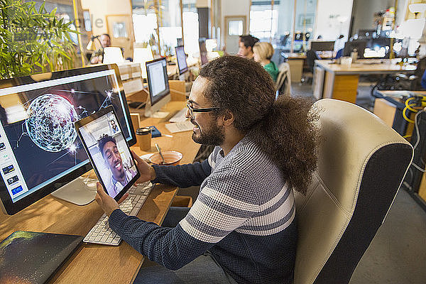 Creative designer video chatting with colleague on digital tablet in office