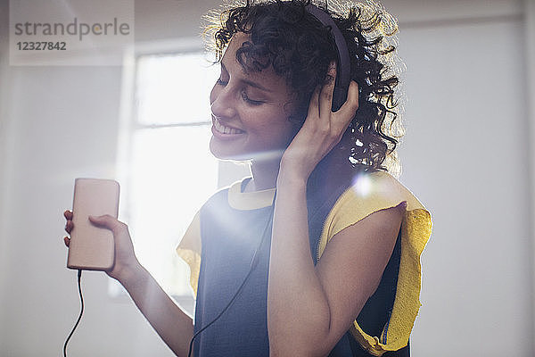 Lächelnde  unbekümmerte junge Frau  die mit Kopfhörern und mp3-Player Musik hört