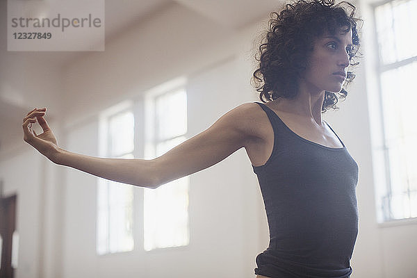 Konzentrierte  entschlossene junge Tänzerin beim Stretching im Tanzstudio