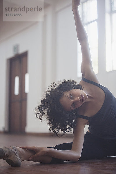 Anmutige junge Tänzerin beim Stretching im Tanzstudio