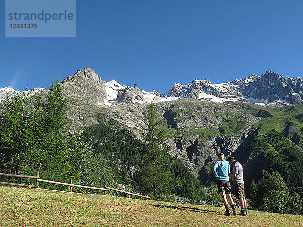 Italia Aoste veny Courmayeur  2 Wanderer stehen vor der italienischen Seite des Mont Blancs