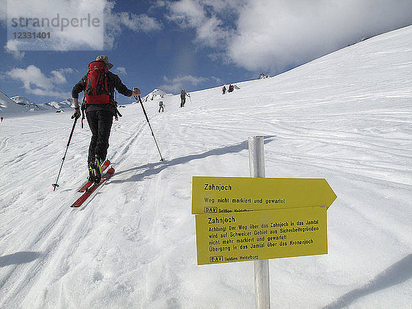 ÖSTERREICH  Tirol  Silvretta Gebirge  ein Langläufer fährt vor einem Wanderschild mit deutscher Aufschrift auf dem Weg zur Larainfernerspitze vorbei