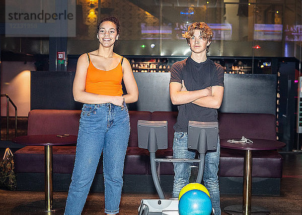 Multi-ethnic friends standing by computer at bowling alley