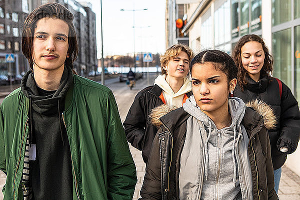 Multi-ethnic teenagers walking on sidewalk in city