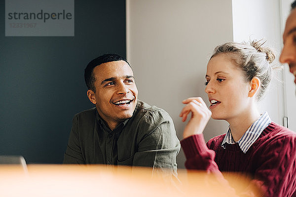 Low angle view of smiling businessman looking at businesswoman in creative office