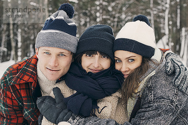 Portrait of friends embracing at park during winter