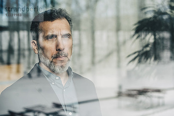 Close-up of thoughtful businessman seen through glass window at office