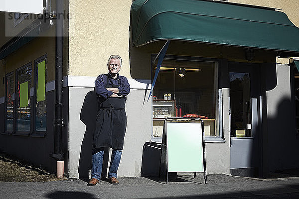 Full length portrait of confident male entrepreneur standing outside store