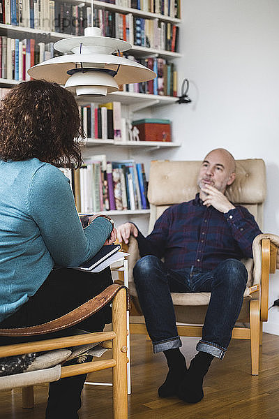 Female therapist talking with male patient at home office