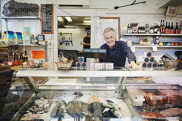 Portrait of smiling male owner standing at counter in store