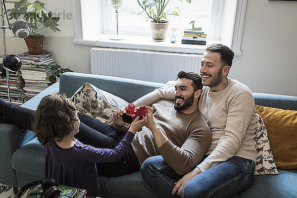 High angle view of daughter showing blocks to smiling fathers in living room