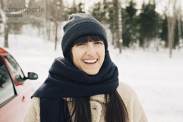 Portrait of smiling woman wearing scarf on snowy landscape