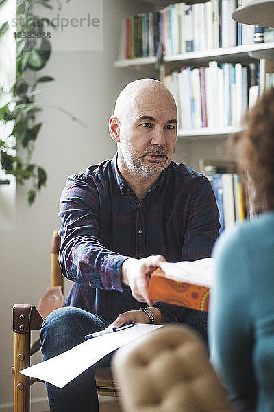 Male therapist giving tissue to female patient during therapy session