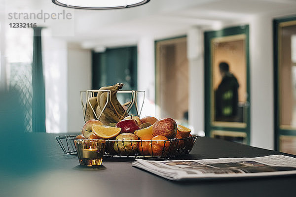 Fruits in basket by newspaper on table at creative office