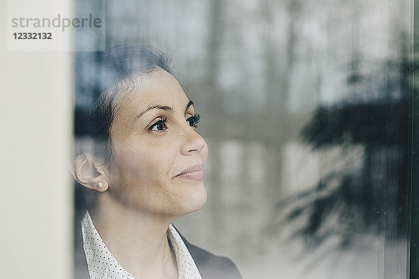 Close-up of thoughtful businesswoman seen through glass window at office