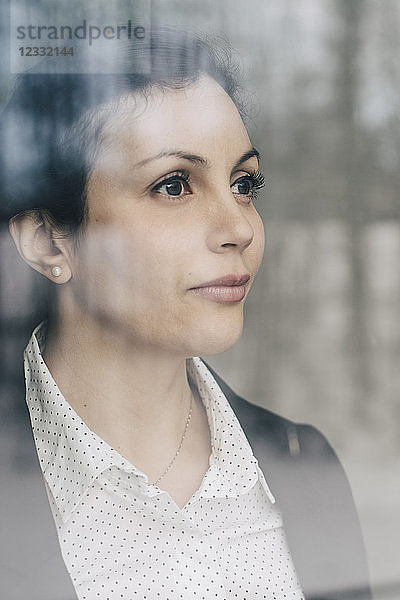 Close-up of thoughtful businesswoman seen through glass window at office