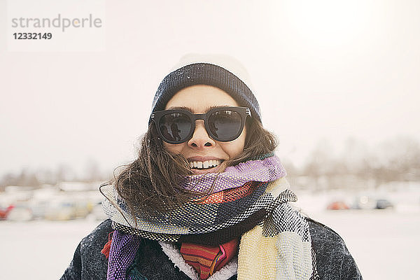 Close-up of smiling woman wearing scarf and sunglasses at park during winter