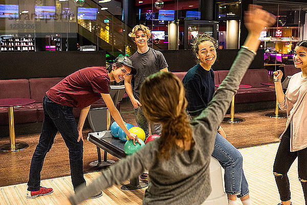 Cheerful multi-ethnic teenagers enjoying at bowling alley