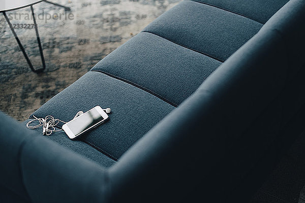 High angle view of smart phone on couch at office in conference