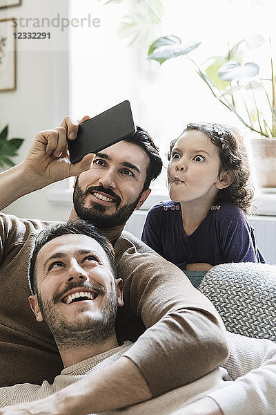 Fathers and playful daughter taking selfie through smart phone at home