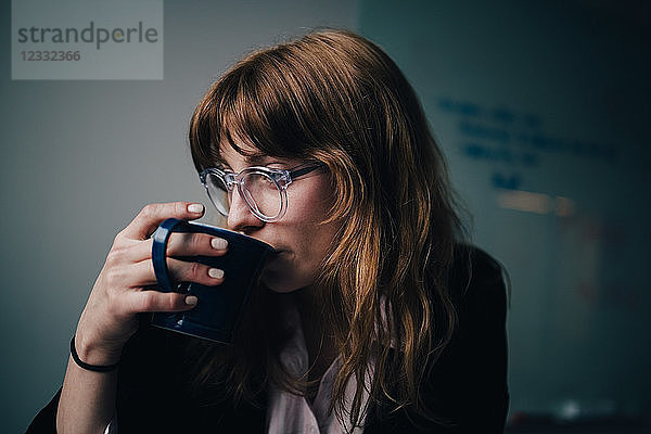 Young businesswoman drinking coffee at creative office