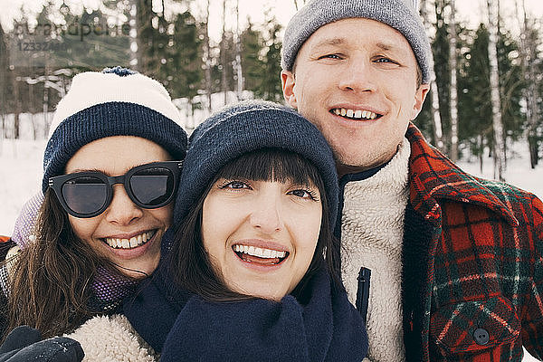 Portrait of cheerful friends wearing knit hats at park during winter