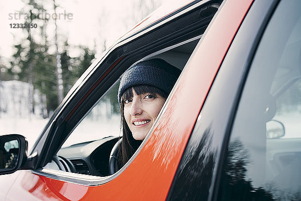 Portrait of smiling woman sitting in red car