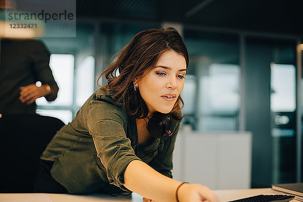 Confident businesswoman working at desk in creative office