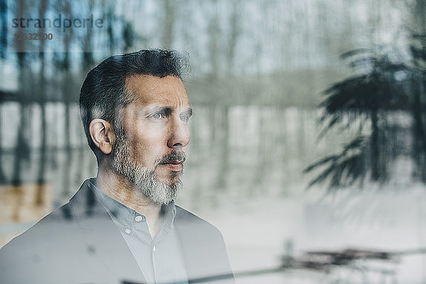 Close-up of thoughtful businessman seen through glass window at office