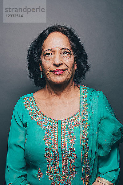 Portrait of confident senior woman wearing salwar kameez on gray background