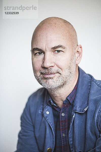 Portrait of mature therapist against white wall at home office