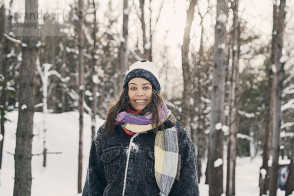 Portrait of smiling mid adult woman standing against bare trees during winter