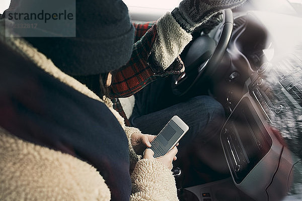 High angle view of woman using smart phone while sitting with friend in car