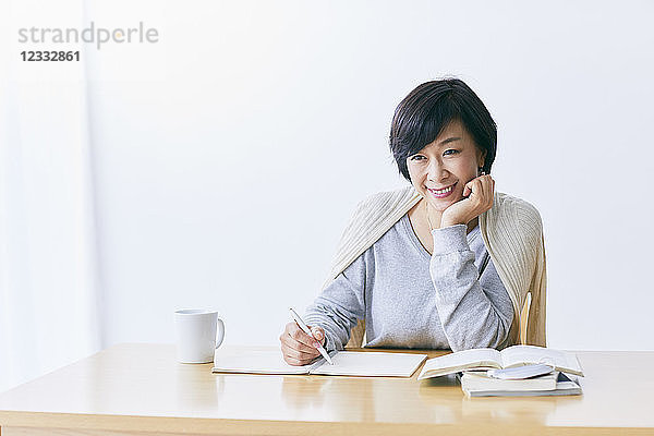 Japanische Seniorin bei der Arbeit am Tisch