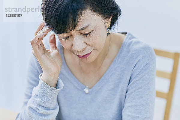 Japanische Seniorin mit Kopfschmerzen