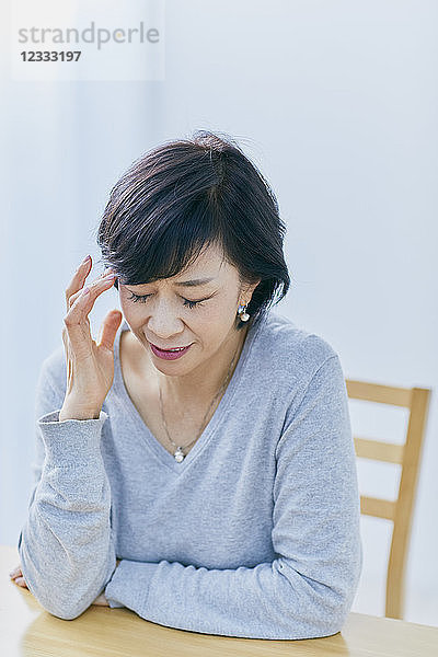 Japanische Seniorin mit Kopfschmerzen