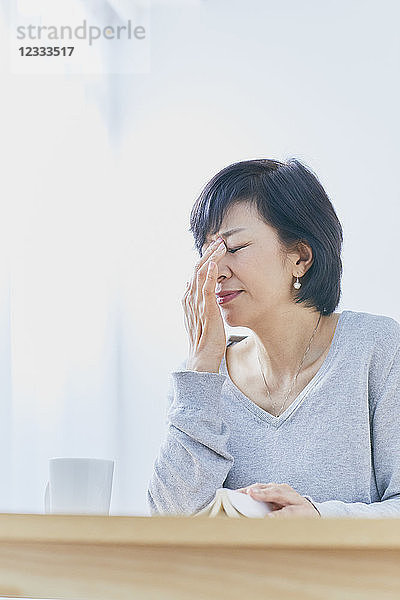 Japanische Seniorin mit Kopfschmerzen