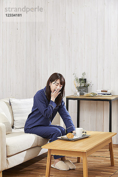 Japanische Frau isst im Pyjama