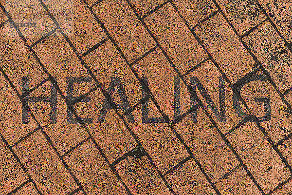 Word 'Healing' stenciled on red pavement