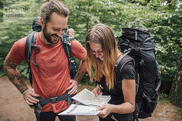 Happy young couple on a hiking trip reading map