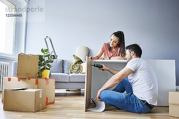 Couple in new apartment assembling furniture together