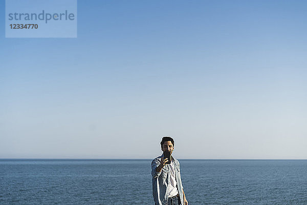 Young man taking selfie with smartphone at the beach