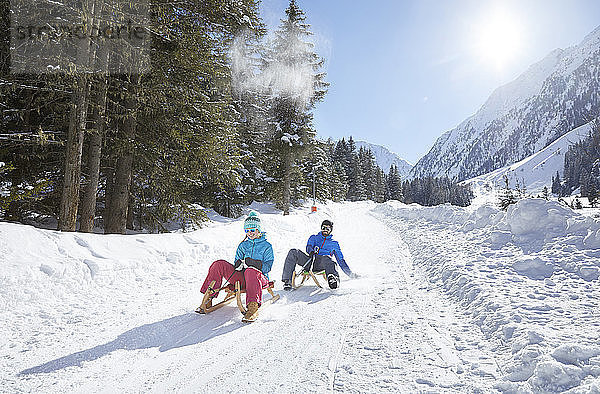 Couple sledding in snow-covered landscape