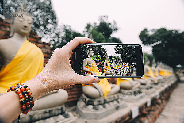 Thailand  Ayutthaya  Wat Yai Chai Mongkhon  taking a photo from Buddha with smartphone