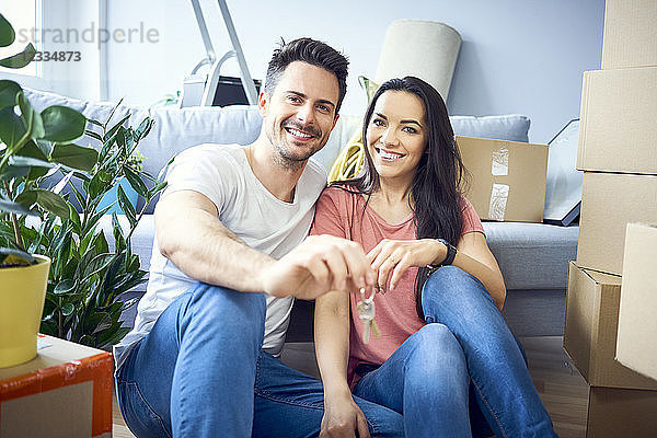 Portrait of happy couple moving in showing keys to new apartment